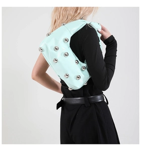 Detail view of mint green hobo bag with large silver metallic studs worn by model