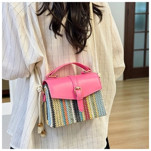 Detail of colorful woven straw shoulder bag featuring pink leather trim and rope strap