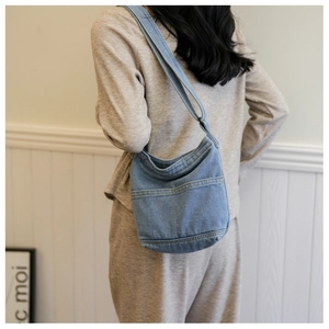 Détail d'un sac bandoulière en jean bleu avec poches latérales et large sangle