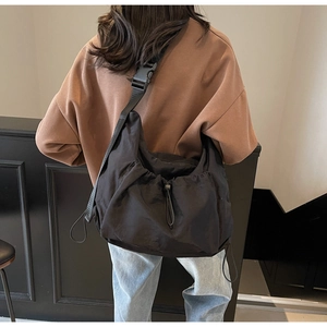 Detail of black nylon crossbody bag featuring drawstring folds and adjustable strap