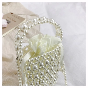 Detailed view of handmade pearl woven bucket bag with elegant satin drawstring pouch