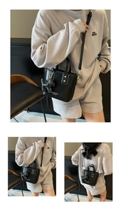 Black leather bucket bag with cute dog pendant shown in front and side carry views
