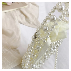 Detailed close-up of woven pearl bucket bag featuring elegant metal lobster clasp