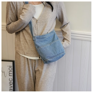 Détail du sac bandoulière en jean bleu avec poches avant sur une tenue minimaliste
