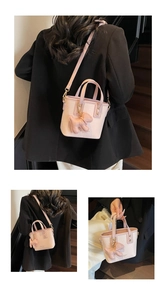 Detailed view of pink leather bucket bag with brand logo and dog-shaped charm accessory