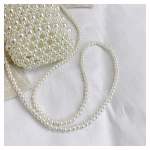 Close-up of a handmade white pearl beaded bucket bag with a matching long strap