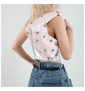 Detail showing pink half-moon hobo bag with silver rivets worn on model's shoulder