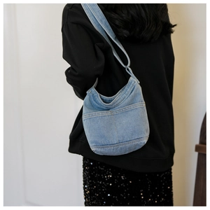 Détail du sac bandoulière en jean bleu clair avec deux poches avant et sangle réglable