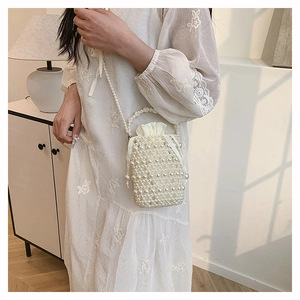 Chic woven pearl bucket bag with drawstring liner shown as a crossbody on a model