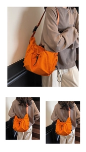 Detail of bright orange nylon crossbody bag featuring drawstring pleated texture and wide strap