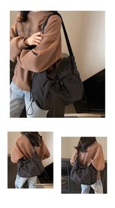 Detail of black nylon tote bag with drawstring pockets and wide shoulder strap