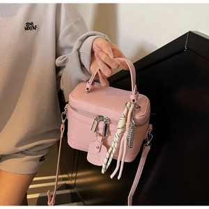 Detailed close-up of pink lychee grain leather crossbody bag with silver zipper and charm