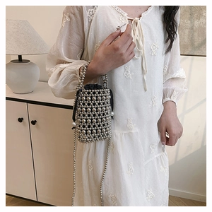 Close-up of woven silver beaded bucket bag with black drawstring and metal luster