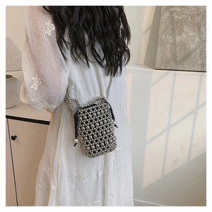 Close-up of black woven bucket bag with silver metal bead mesh and chain strap