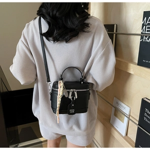 Détail du mini sac à main en cuir litchi noir avec poignée et étiquette tressée
