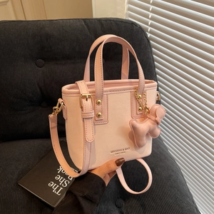 Pink PU leather mini bucket bag with dual handles and puppy charm pendant shown in hand