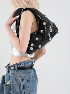 Fashionable black hobo bag with silver metallic rivets shown on shoulder of a model