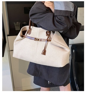 Close-up of woven tote bag featuring contrast leather trim and golden metal buckle details