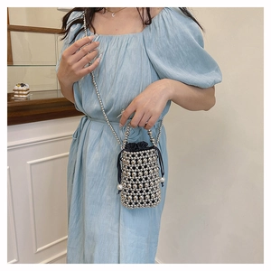 Mini woven bucket bag with silver beads and pearls worn by model in a cozy cafe setting