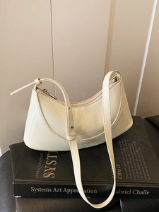 Chic beige patent leather baguette bag with NO FILTER print on a stylish book