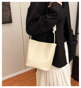 Close-up of cream white bucket bag with pebble leather texture and braided strap details