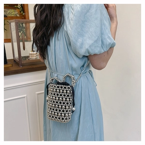 Detail of silver beaded bucket bag with pearl accents and black drawstring liner on model