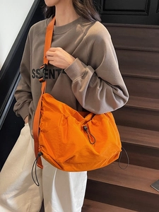 Bright orange nylon drawstring crossbody bag with adjustable wide strap in streetwear style