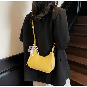 Détail du sac croissant jaune avec texture lychee et décoration de nœud en perles