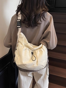 Cream large nylon crossbody bag with drawstring design and black wide strap on a model