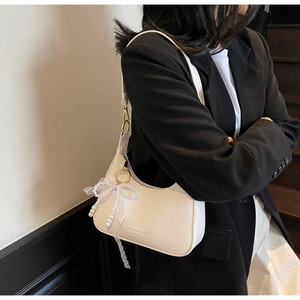 Détail du sac hobo en cuir blanc avec nœud en dentelle et perles et logo doré