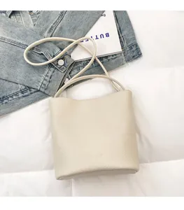 Detail of creamy white bucket bag in lychee pattern leather with embossed fashion logo
