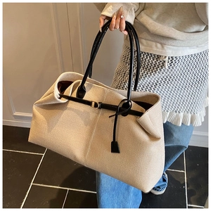 Detail of the high-capacity tote bag with beige canvas material and black leather handles