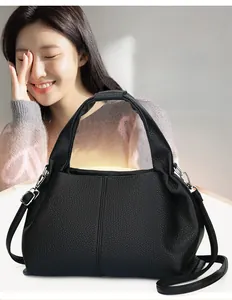 Detail of black lychee grain leather handbag with silver hardware and removable shoulder strap
