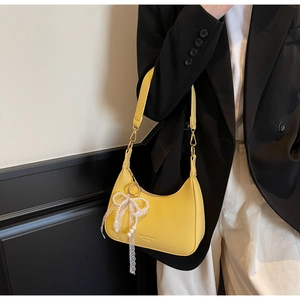 Détail du sac bandoulière demi-lune jaune avec pendentif perle et nœud en dentelle chic
