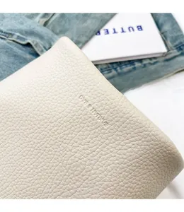 Macro shot of cream white lychee grain leather texture with embossed brand logo detail