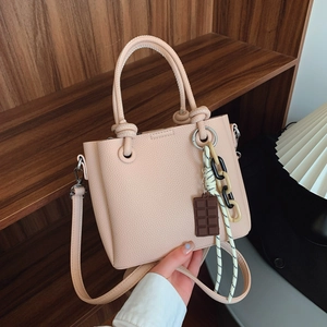 Sac seau minimaliste en cuir beige avec pendentif chocolat et bandoulière réglable