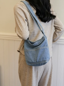 Sac hobo en denim bleu clair avec coutures contrastées jaunes et poches avant sur modèle