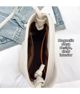 Detail view of the magnetic closure and spacious interior compartments of the cream bucket bag