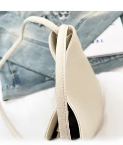 Detail of comfortable shoulder strap and soft pebble leather texture on white bucket bag