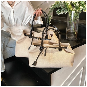 Detail view of large and small canvas tote bags with black leather handles and trim