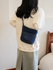 Sac bandoulière minimaliste en jean bleu marine avec doubles poches sur un modèle