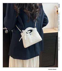 Quilted crossbody bag with lace bow detail shown in a side-view lifestyle shot