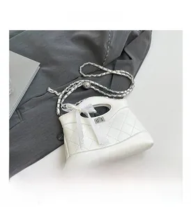 Detail view of white quilted bucket bag with lace bow and silver chain strap
