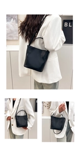Detail of black lychee-textured bucket bag showing hand-carry and crossbody versatile styles