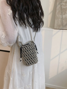 Mini silver beaded bucket bag with pearls and chain strap shown on a model