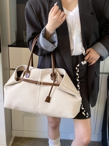 Large beige canvas tote bag with brown leather handles and buckle details for women