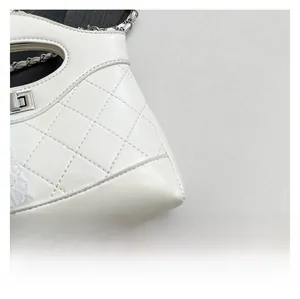 Close-up of quilted white leather bucket bag with silver lock and lace detailing