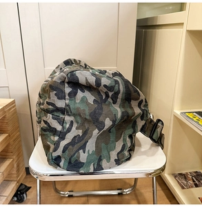 Detail of canvas shoulder bag showing jungle camo pattern and adjustable side buckle
