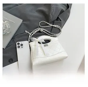 Close-up of quilted chain bag with white lace bow and silver adjustment ball detail