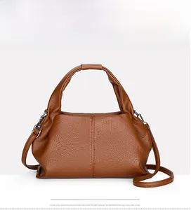 Detail view of brown lychee grain leather handbag with round handle and silver hardware